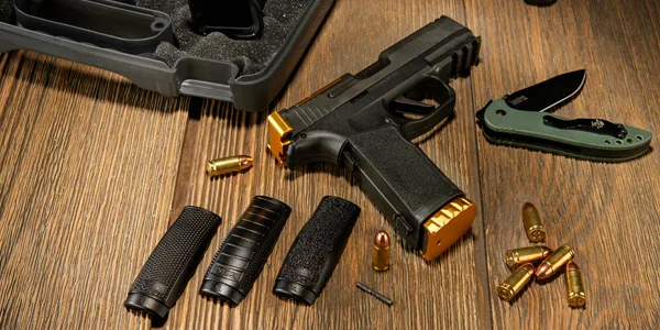 Pistol with gold NDZ firearm parts, interchangeable grips, and ammunition displayed on a wooden surface.