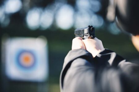 Close-up of a shooter aiming at a paper target to improve shooting accuracy during target practice, showing precise shot groupings on the bullseye