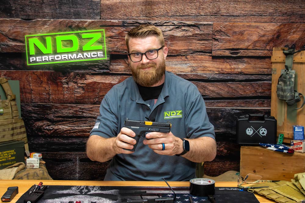 YouTube thumbnail showing Justin from NDZ holding an upgraded Ruger RXM pistol with NDZ Performance parts, alongside bold text “Ruger RXM Upgrade – Full NDZ Install + Review.”