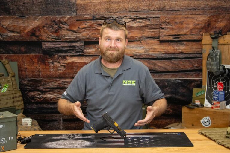 NDZ Performance team member presenting completed Glock clone build on workbench with American flag backdrop