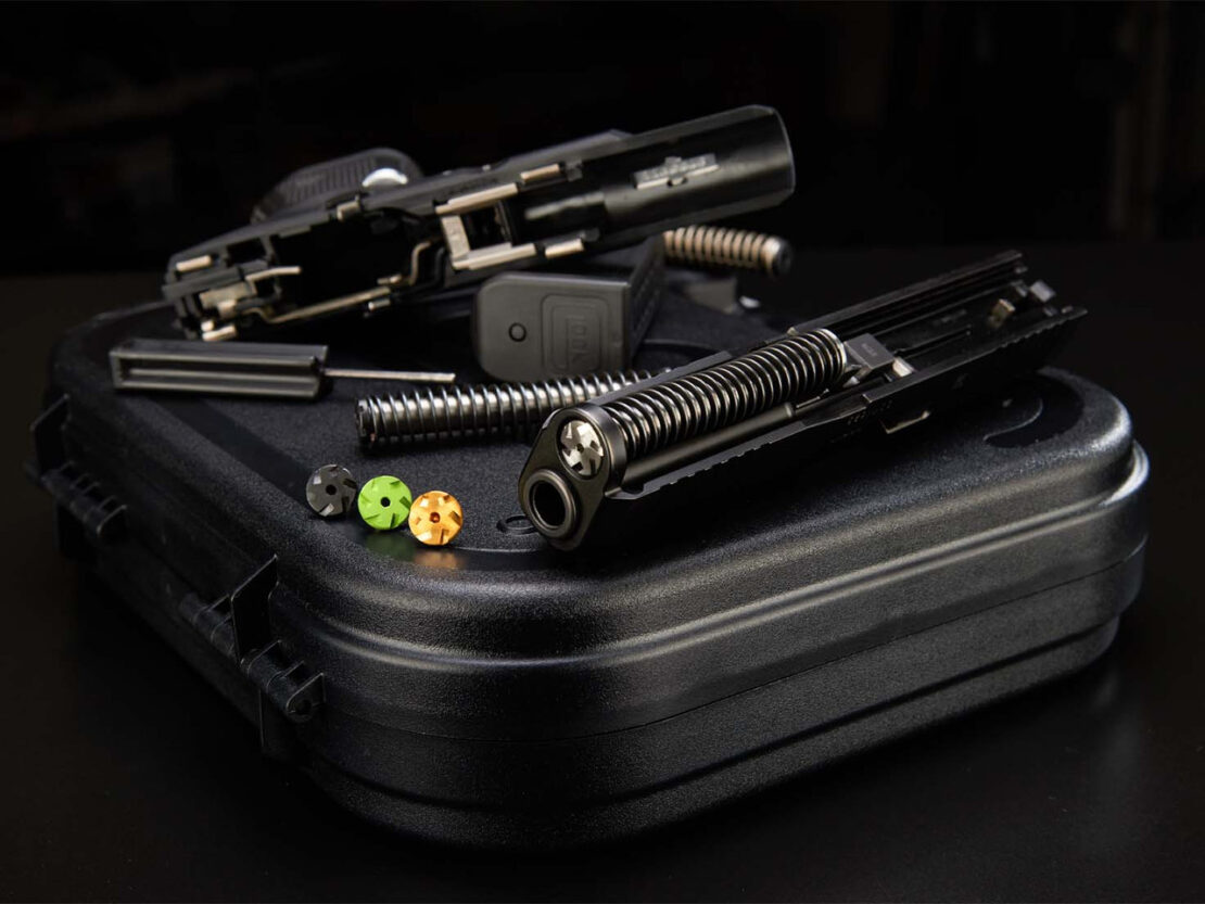 NDZ Performance heavyweight guide rod upgrade for Glock 19 with stainless steel construction, recoil spring, and colored tuning washers displayed alongside disassembled Glock pistol slide and frame.