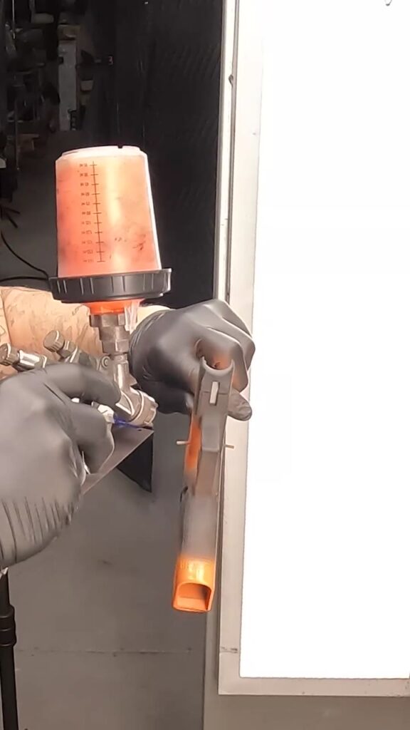 Spraying the orange Cerakote base coat on the Glocktober giveaway build's frame.